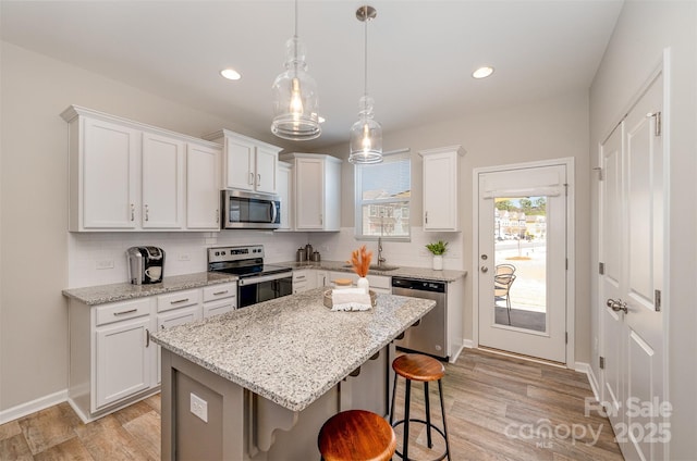 kitchen with light wood finished floors, backsplash, a kitchen breakfast bar, and stainless steel appliances