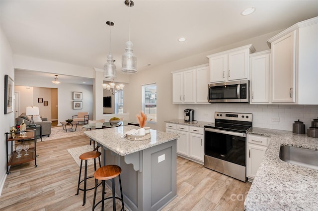 kitchen with light wood finished floors, decorative backsplash, appliances with stainless steel finishes, and a kitchen island