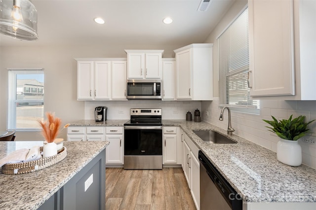 kitchen featuring visible vents, light wood-type flooring, appliances with stainless steel finishes, white cabinetry, and a sink