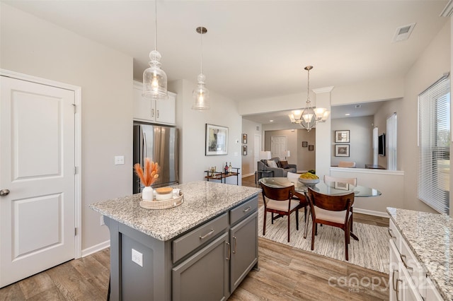 kitchen featuring light wood-style flooring, gray cabinetry, a kitchen island, and freestanding refrigerator