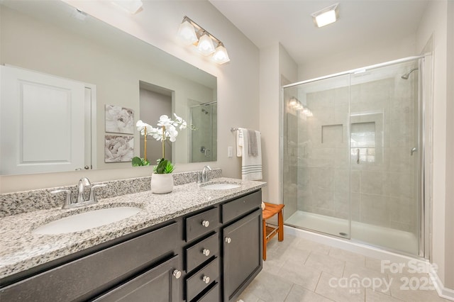 full bathroom with a sink, a stall shower, double vanity, and tile patterned flooring