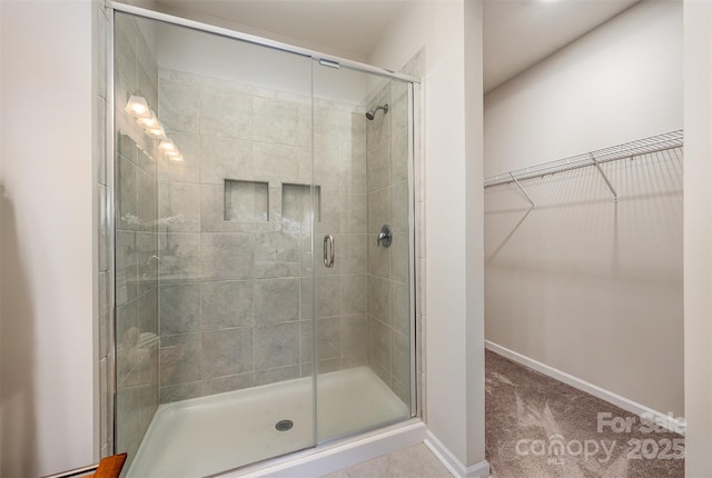 bathroom featuring baseboards, a stall shower, and a spacious closet