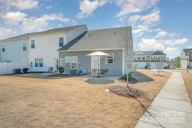 back of house with a patio area, roof with shingles, central AC, and fence