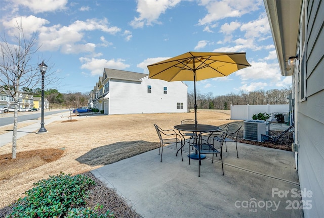 view of patio featuring central air condition unit, outdoor dining area, and fence