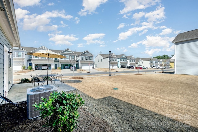 view of yard with a residential view, central AC unit, and a patio