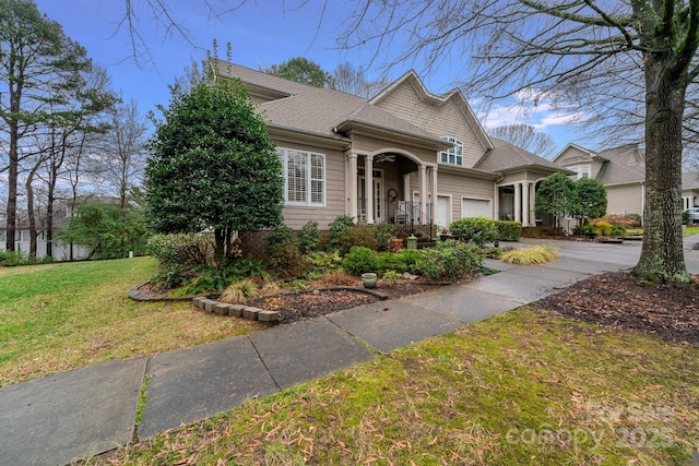 view of front of property featuring a front lawn, concrete driveway, an attached garage, and roof with shingles