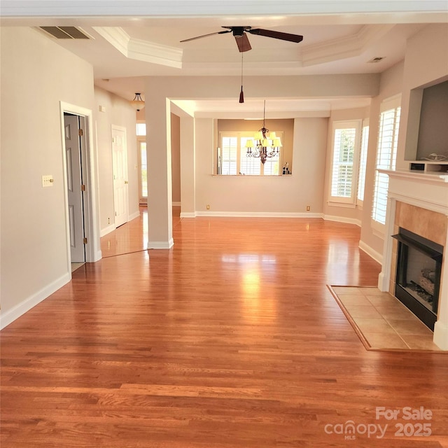 unfurnished living room featuring visible vents, crown molding, light wood-type flooring, a fireplace, and a raised ceiling