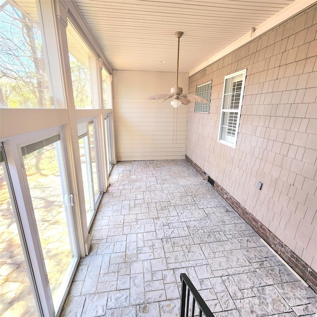 unfurnished sunroom featuring plenty of natural light and ceiling fan