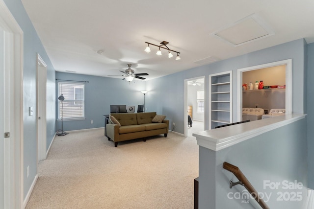 living area with attic access, baseboards, washer and clothes dryer, light colored carpet, and built in shelves