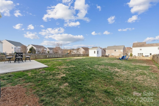 view of yard featuring a fenced backyard, a residential view, an outbuilding, and a patio