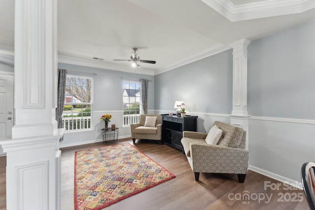 living area featuring visible vents, ornamental molding, a ceiling fan, wood finished floors, and ornate columns