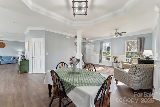 dining space with ornate columns, crown molding, stairs, and wood finished floors