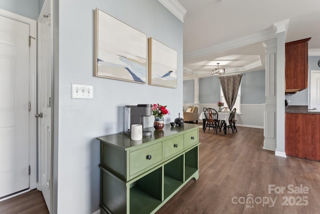 hall featuring a tray ceiling, dark wood-style flooring, crown molding, and an inviting chandelier