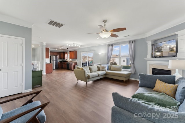 living room featuring wood finished floors, visible vents, and crown molding