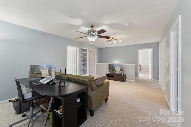 office featuring a ceiling fan, light colored carpet, and baseboards