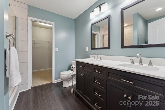 full bath featuring double vanity, a sink, toilet, and wood finished floors