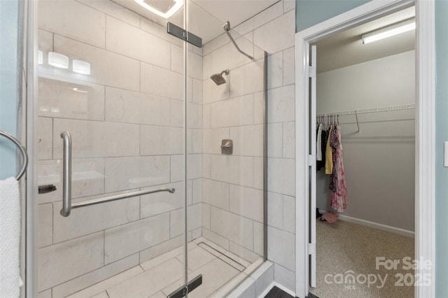 bathroom featuring a shower stall, baseboards, and a spacious closet