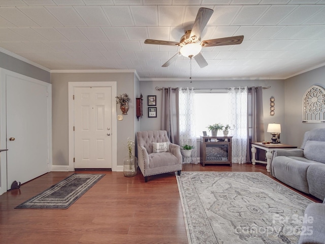 living area with a ceiling fan, crown molding, wood finished floors, and baseboards