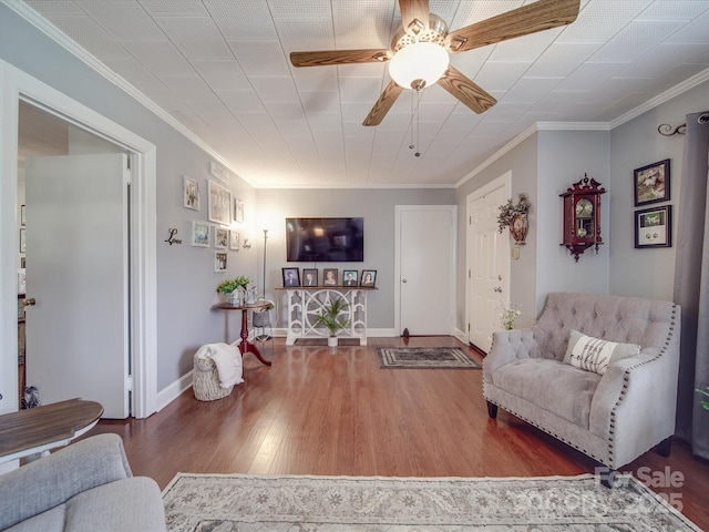 living area with ornamental molding, baseboards, a ceiling fan, and wood finished floors
