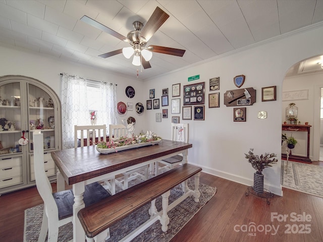 dining room with baseboards, ceiling fan, ornamental molding, wood finished floors, and arched walkways