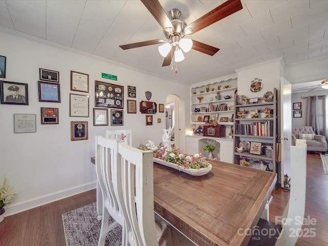 dining space featuring crown molding, wood finished floors, arched walkways, and ceiling fan