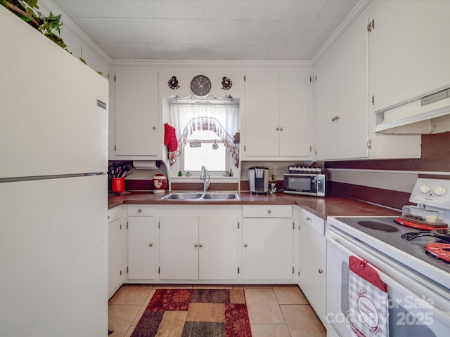 kitchen with a sink, white appliances, dark countertops, and light tile patterned flooring