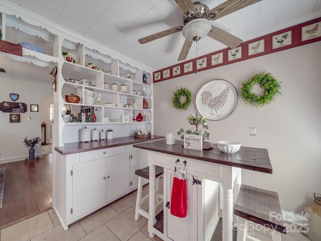kitchen featuring light tile patterned floors, a ceiling fan, open shelves, white cabinetry, and dark countertops