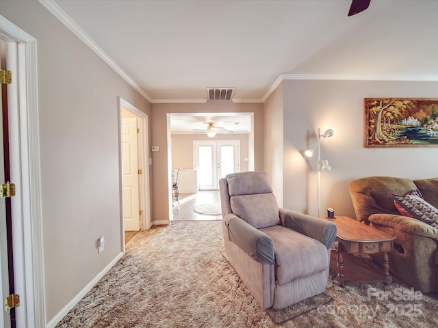 living area featuring visible vents, carpet, crown molding, baseboards, and ceiling fan