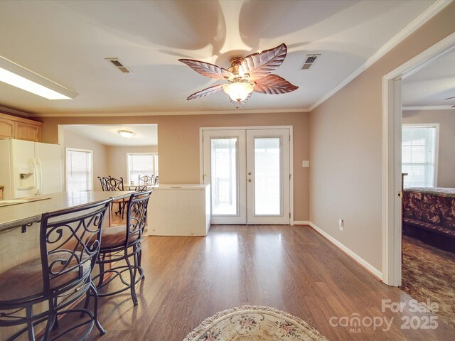 interior space with wood finished floors, baseboards, ceiling fan, french doors, and crown molding