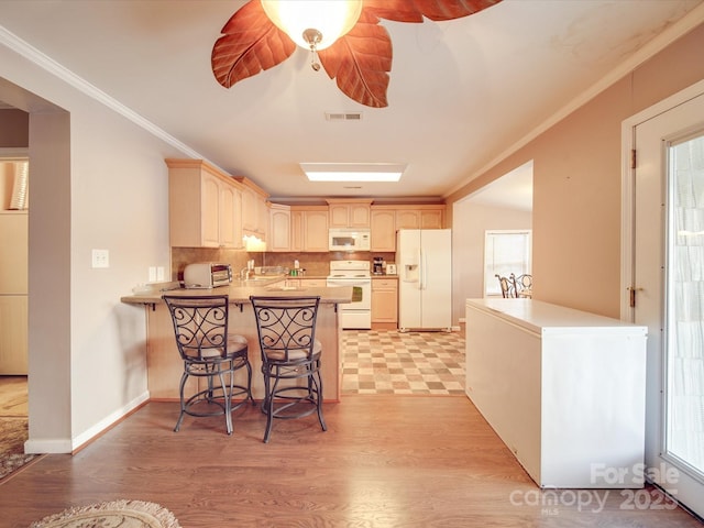 kitchen featuring white appliances, crown molding, a peninsula, and visible vents