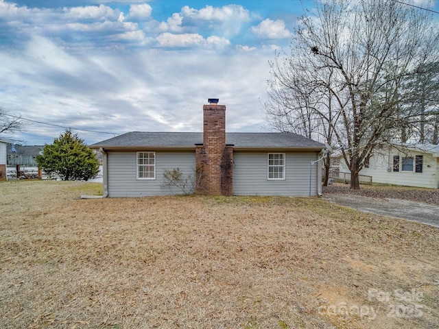 back of property featuring a lawn and a chimney