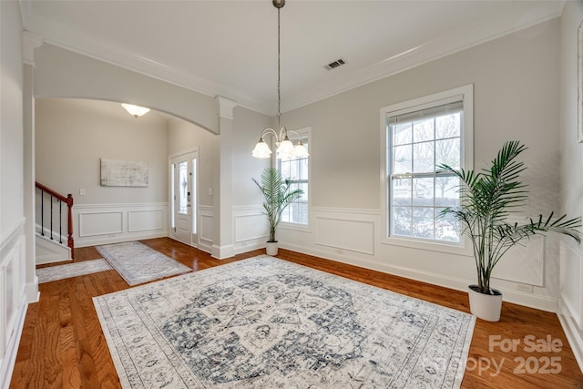 entrance foyer with visible vents, wood finished floors, stairway, arched walkways, and crown molding