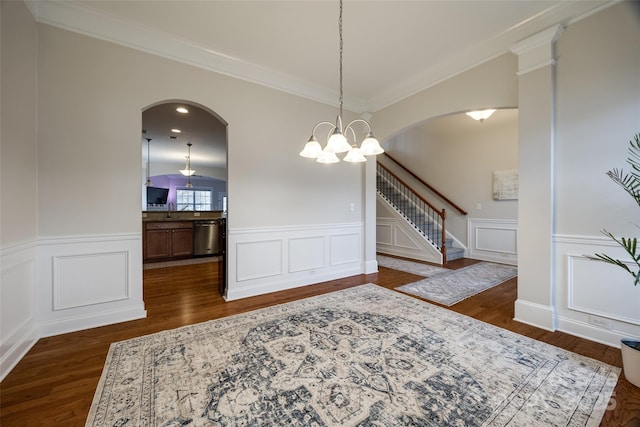 dining area featuring arched walkways, an inviting chandelier, dark wood finished floors, and wainscoting