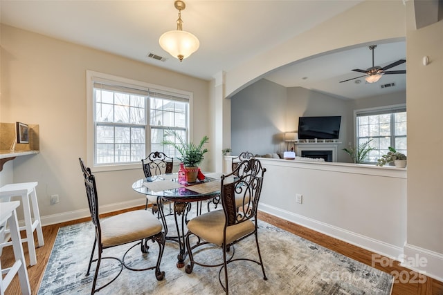 dining room featuring visible vents, plenty of natural light, arched walkways, and wood finished floors