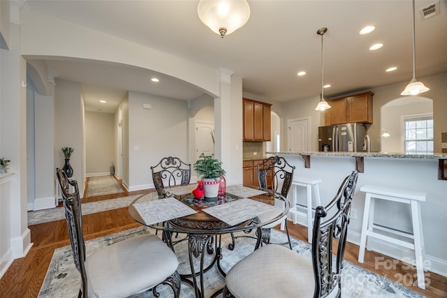 dining area featuring light wood-type flooring, visible vents, recessed lighting, arched walkways, and baseboards