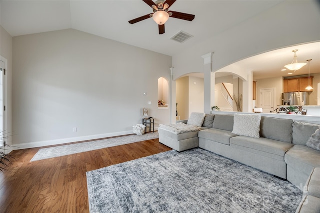 living area with visible vents, baseboards, wood finished floors, arched walkways, and a ceiling fan