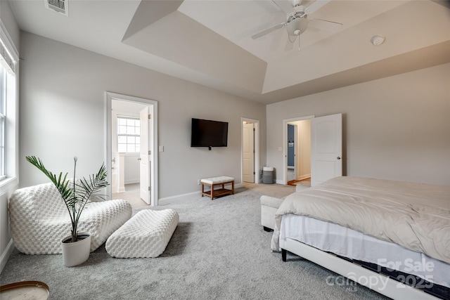 carpeted bedroom with visible vents, a raised ceiling, and baseboards