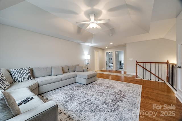 living room featuring a ceiling fan, wood finished floors, baseboards, recessed lighting, and a raised ceiling