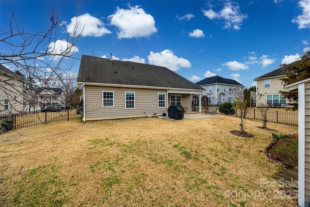 rear view of property featuring a patio, a yard, and a fenced backyard