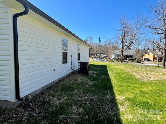 view of side of property featuring cooling unit and a yard
