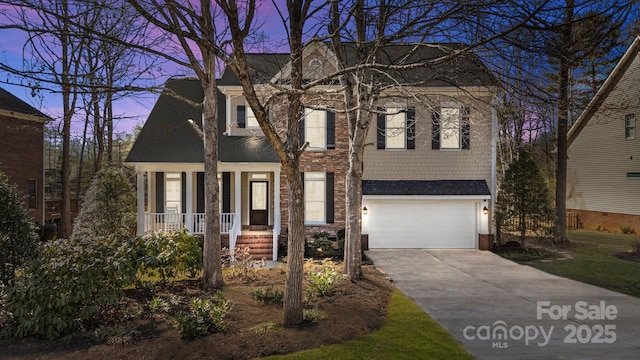 view of front of house featuring covered porch, concrete driveway, an attached garage, and a shingled roof