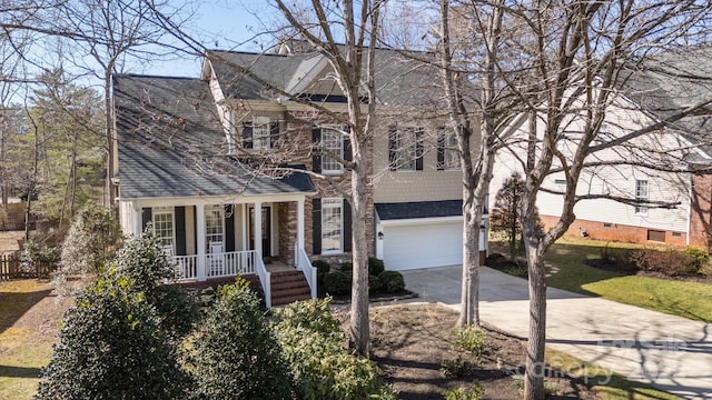 view of front of home with a garage, roof with shingles, a porch, and driveway