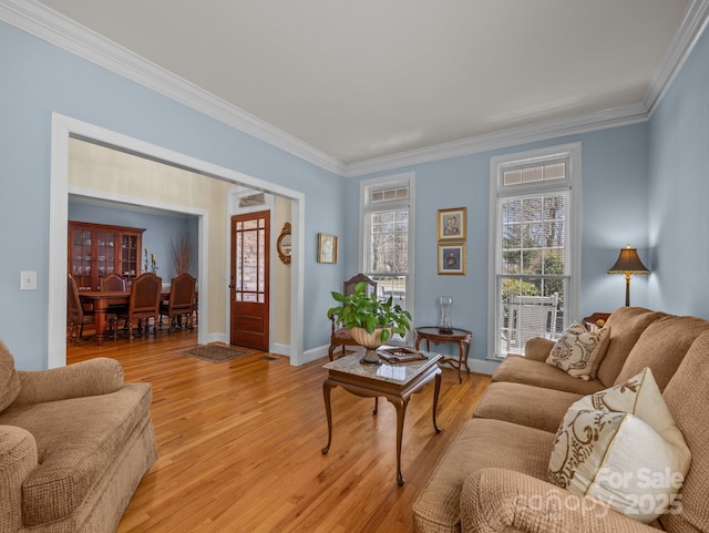 living area with light wood-style floors, baseboards, and ornamental molding