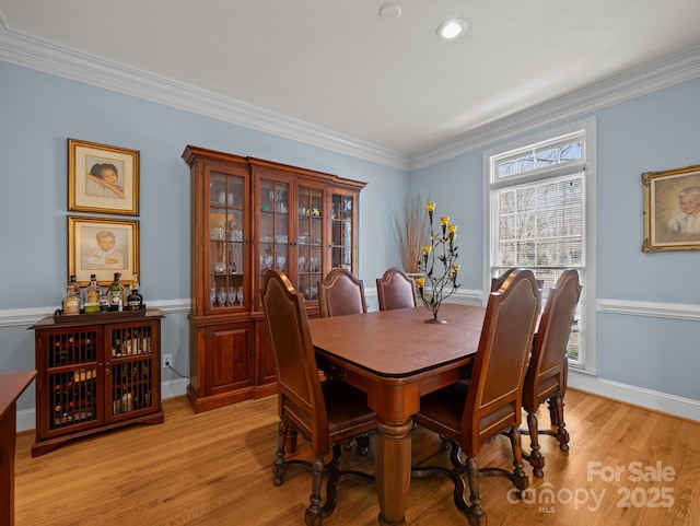 dining area featuring crown molding, baseboards, and light wood finished floors