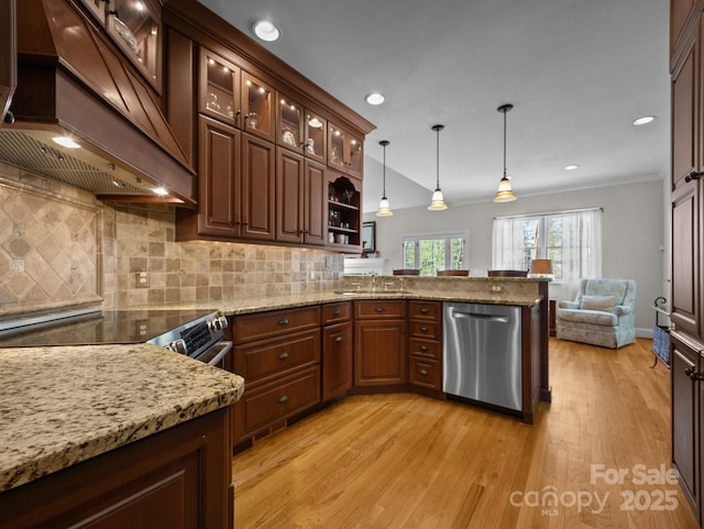 kitchen with custom range hood, appliances with stainless steel finishes, a peninsula, light wood finished floors, and decorative backsplash