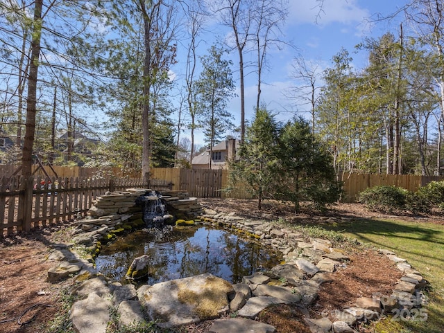 view of yard featuring a small pond and a fenced backyard