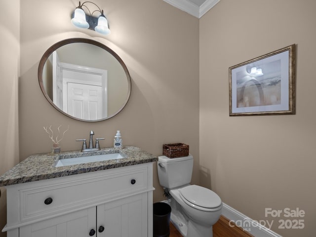 half bathroom with baseboards, toilet, ornamental molding, and vanity