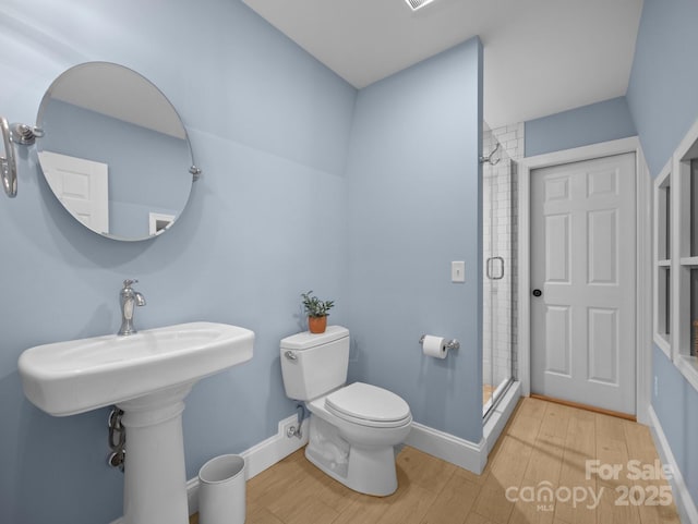 full bathroom featuring toilet, wood finished floors, a stall shower, and baseboards