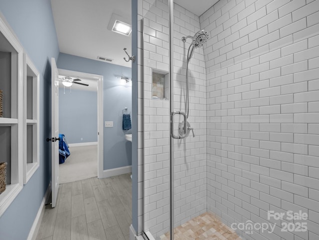 bathroom with wood finished floors, baseboards, a ceiling fan, visible vents, and a stall shower