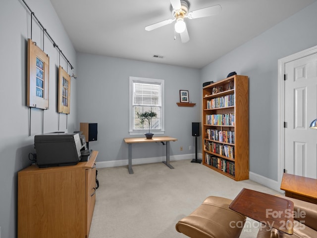 office space featuring light colored carpet, a ceiling fan, and baseboards